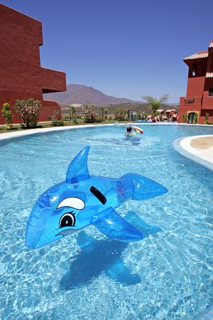 Inflatable toy dolphin on blue swimming pool on spanish vacation urbanisationの写真素材