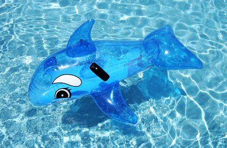 Inflatable toy dolphin on blue swimming pool on spanish vacation urbanisationの写真素材