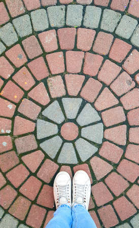 Girl's legs on patterned street tiles circle.