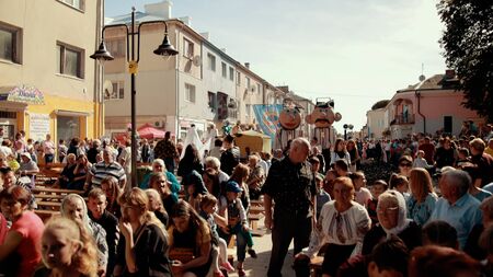 KAMENKA BUZKA, UKRAINE - SEPT 14, 2019: holiday on street, local parade, there are people in variety of costumes and men and women in carnival costumes and masks, around a lot of spectatorsのeditorial素材