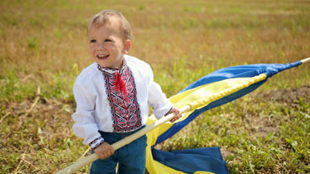Son waving ukrainian flag on wheat field, lonely patriot man standing, looking at the sunrise with flag of ukraine. Happy boy is a patriot of his country. Yellow-blue symbol. Independence dayの写真素材