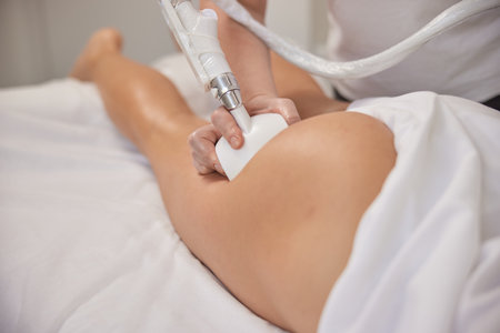 vacuum-roller manipulator, massage salon, body correction. Young woman in beauty salon doing beauty services, body shaping. Masseur is making vacuum roller massage for client, figure correctionの写真素材