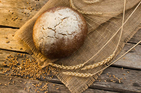 Loaf of black bread on old wooden table, the rays of the morning sunの写真素材