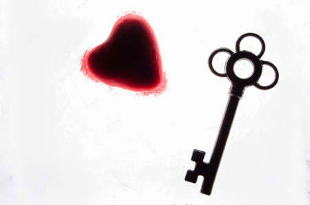 Silhouette of a red heart and key on white background