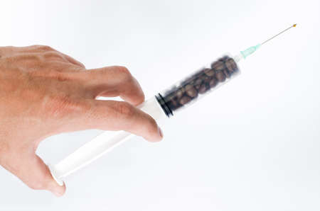 Male hand holding a syringe with coffee beansの写真素材