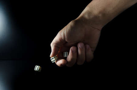 Male hand throwing dice on a black backgroundの写真素材