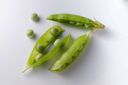 Pods of green peas on a white surfaceの写真素材