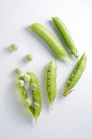 Pods of green peas on a white surfaceの写真素材