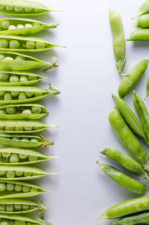 Pods of green peas on a white surface