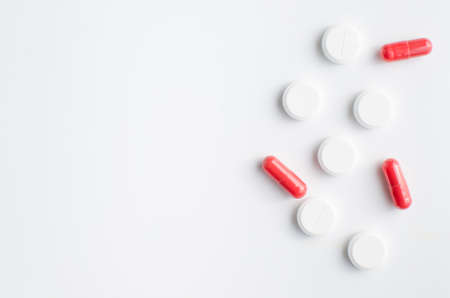 A few red and white pills on white background