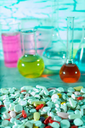 A large variety of medicinal pills on the background of vials and flasks filled with liquidの写真素材