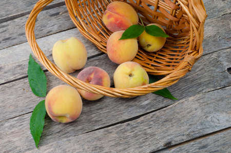 Wooden bowl with peaches on wooden backgroundの写真素材
