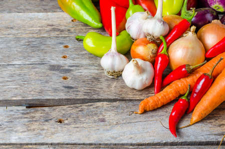 Vegetables carrots eggplant garlic peppers onion and on wooden backgroundの写真素材