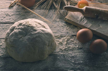 Dough, rolling pin and wheat ears on the old wooden background flouredの写真素材