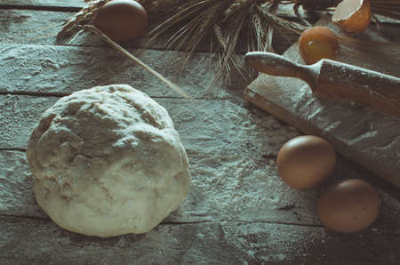 Dough, rolling pin and wheat ears on the old wooden background flouredの写真素材