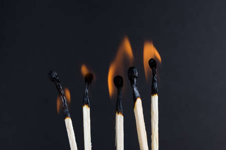 Burning matches with orange flames on a black backgroundの写真素材
