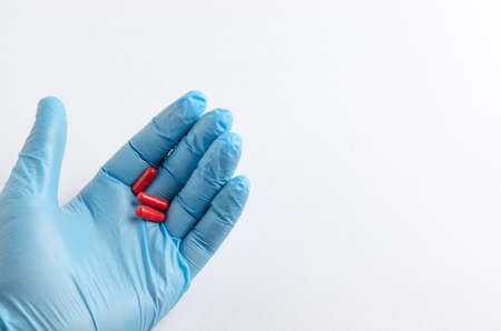 The hand of health care worker in blue medical gloves holding a pillの写真素材