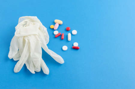 Medical gloves white colored tablets and pills on blue background closeupの写真素材