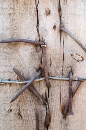 Barbed wire nailed to an old Board with rusty nailsの写真素材