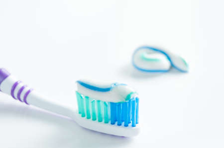 Toothbrush and applied toothpaste on white background