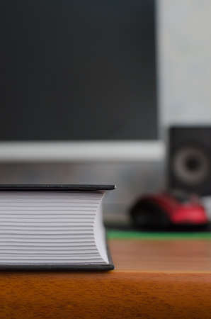 A book with many pages in the foreground, on the background of the computer monitorの写真素材