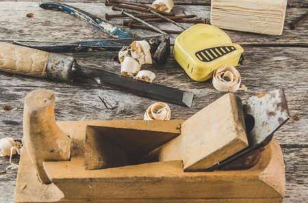 The carpenter tools on wooden bench, plane, chisel,mallet, tape, hammer, tongs, nails and saw the...