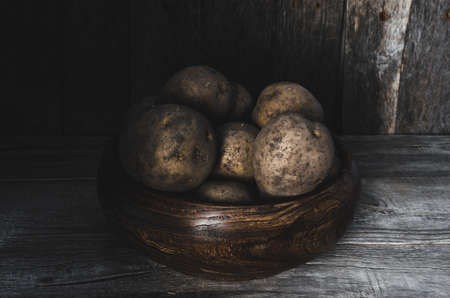Potatoes in a wooden Cup on wooden backgroundの写真素材