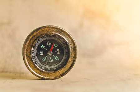 Compass on old map background with falling sun ray on itの写真素材