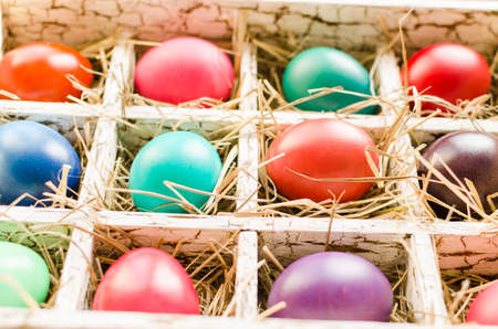 Easter eggs in a wooden box with hay lit by daylightの写真素材