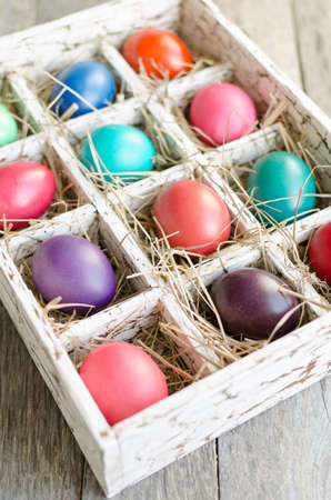 Easter eggs in a wooden box with hay lit by daylight