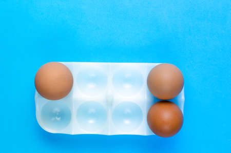 Three brown eggs in stand for egg on a blue background.