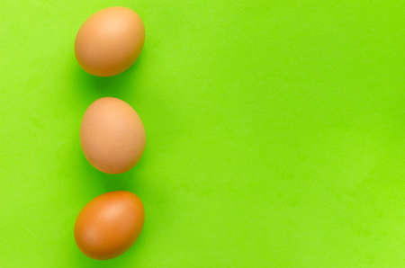 Three brown eggs on a bright light green background.Close upの写真素材