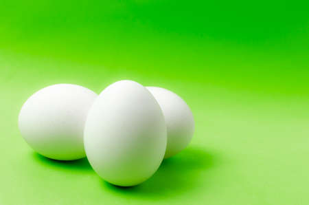 Three chicken eggs on a bright green background.Food close up.の写真素材