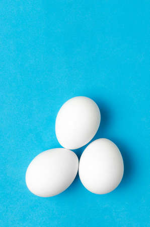 White chicken eggs on blue background, close up.の写真素材