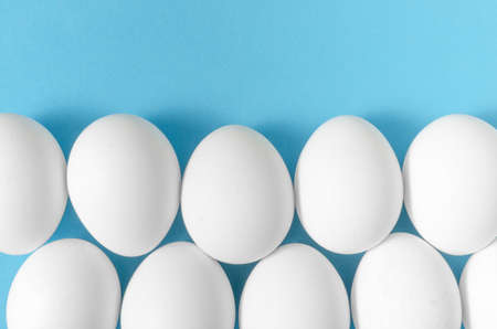 White chicken eggs on blue background.