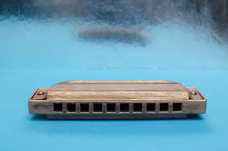 Old harmonica on a blue background.の写真素材