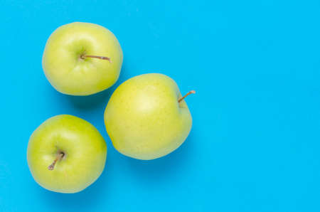 Green apples on a bright, clean, blue background. Close up.の写真素材