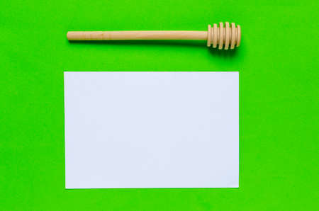 Stick to honey and white sheet of paper on a green background.Horizontal photo.の写真素材