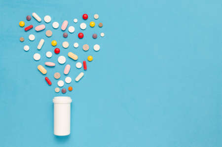 Variety of tablets and pills.Pharmaceuticals and antibiotics heart-shaped bottle on blue background.Capsules medicine.の写真素材