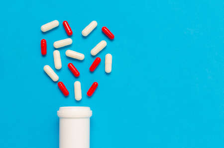 Variety of tablets and pills.Pharmaceuticals and antibiotics heart-shaped bottle on blue background.Capsules medicine.の写真素材