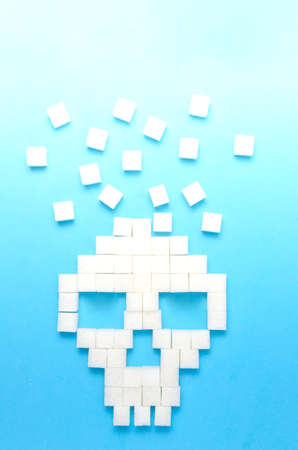 Refined sugar on blue background.Sugar cubes in form of skull.Concept of healthy eating, addiction to candy.Closeup.の写真素材