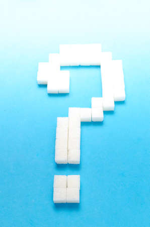Refined sugar in the form of a question mark on a blue background.The concept of sweet life.