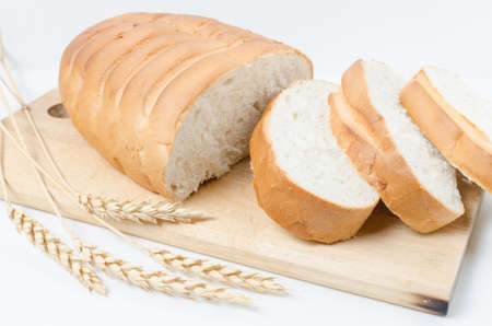 Slices of sliced bread and wheat on a white background close-up.
