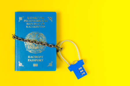 Passport of Kazakhstan is wrapped in chain closed on lock.On yellow background.