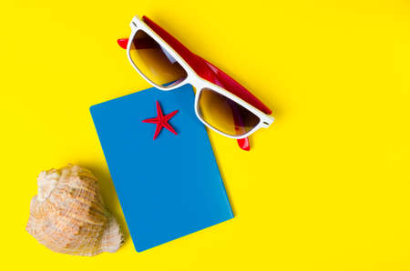 Passport, glasses and shells with star on yellow background.Summer travel.の写真素材