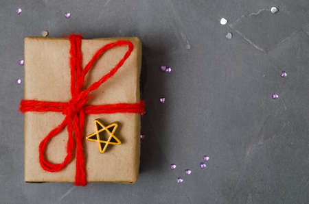 Christmas gift wrapped in paper and tied with red thread. New years day, womens day.On the concrete.