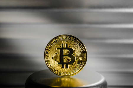 Gold coin cryptocurrency bitcoin on metal stand close-up.