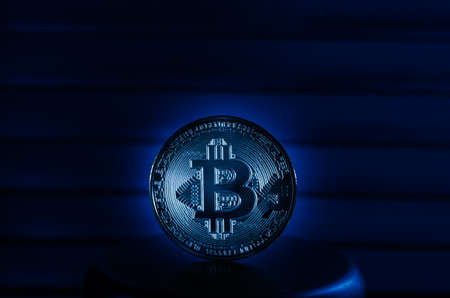 Coin cryptocurrency bitcoin on a metal stand, in blue light close-up.の写真素材