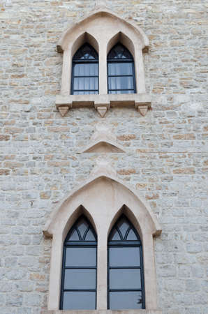 Old Gothic Windows in the shape of a peak in a stone building close-up.の写真素材