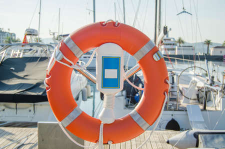 Orange lifebuoy in the port on background of yachts and boats.On a bright Sunny day.